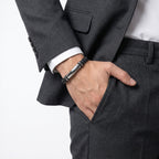 Elini cebine koyan erkeğin bileğinde siyah beyaz örgü deri ve gümüş plaka