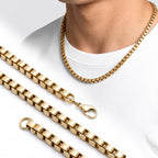 Beyaz tişörtlü erkeğin boynunda AZAROO Forge Anvil gold kare arnavut kolye, yanında zincir parçaları