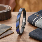 Ahşap masada deri kemerin yanında dik duran mavi siyah örgü bileklik