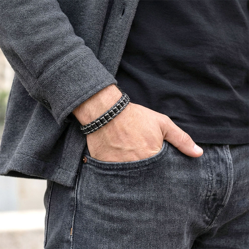 Gri hırka ve kot pantolonla cebine el koyan erkeğin bileğinde siyah küp oniks