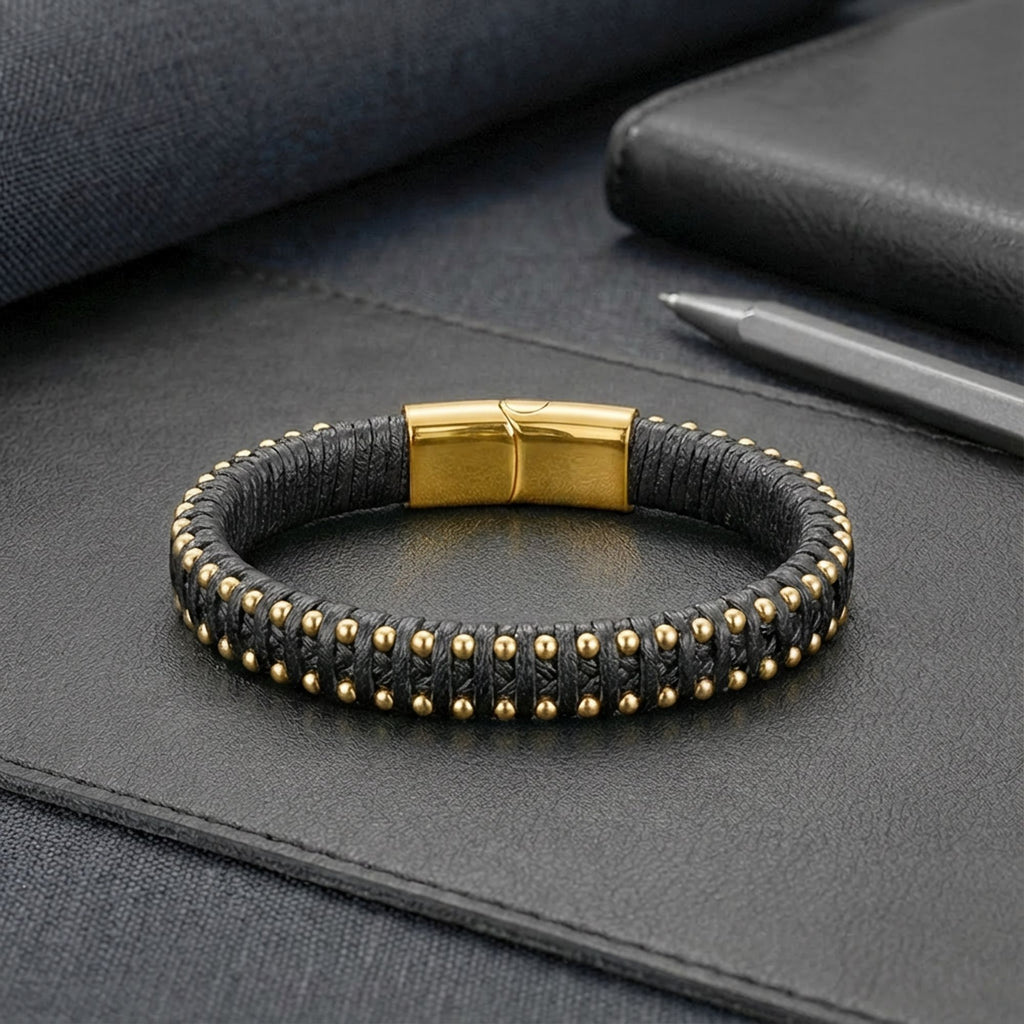 Siyah sümen ve kalem yanında yatay yatan AZAROO Heron gold bileklik